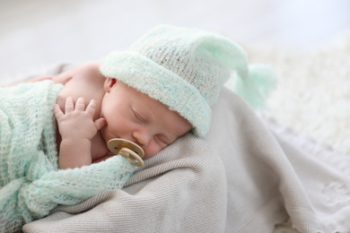 Cute newborn baby in warm hat sleeping on plaid