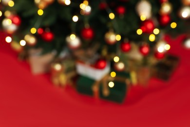 Blurred view of beautifully decorated Christmas tree on red background, closeup