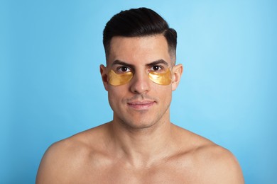 Man with golden under eye patches on light blue background