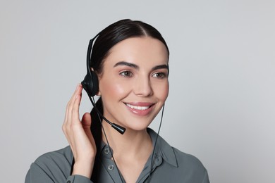 Photo of Hotline operator with modern headset on light grey background. Customer support