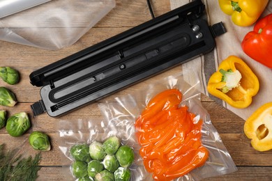 Vacuum packing sealer and different food products on wooden table, flat lay