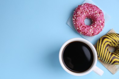 Photo of Tasty frosted donuts and cup of coffee on light blue background, flat lay. Space for text