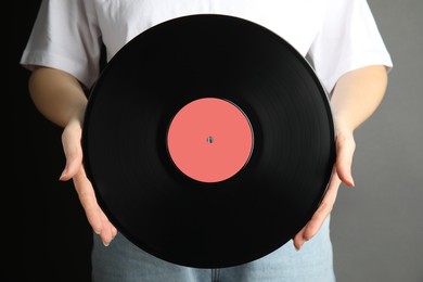 Woman holding vintage vinyl record on grey background, closeup