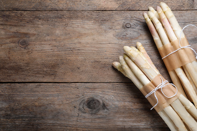 Bunches of fresh white asparagus on wooden table, flat lay. Space for text
