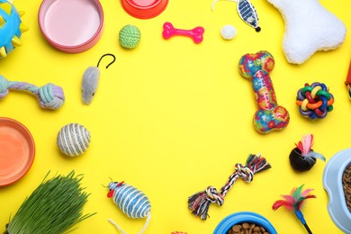 Different pet toys and feeding bowls on yellow background, flat lay. Space for text