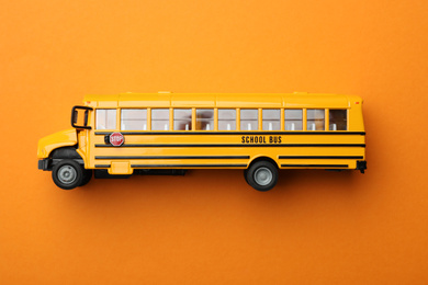Yellow school bus on orange background, top view. Transport for students