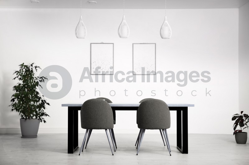 Photo of Stylish wooden table and chairs in light room. Modern interior design
