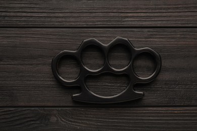 Brass knuckles on black wooden background, top view