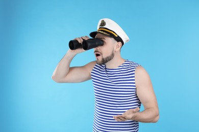 Sailor looking through binoculars on light blue background
