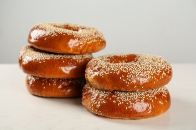 Delicious fresh bagels with sesame seeds on white wooden table