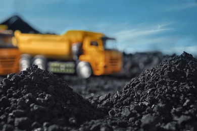 Pile of coal and blurred yellow truck on background, closeup