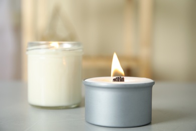 Burning candles in holders on light grey table