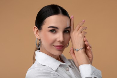 Photo of Young woman with elegant jewelry on beige background