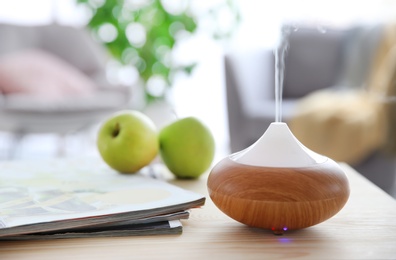 Aroma oil diffuser on table against blurred background