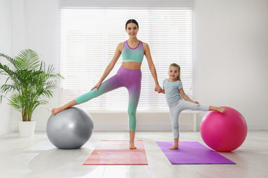 Woman and daughter doing exercise with fitness balls at home