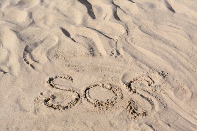 SOS message written on sandy beach outdoors