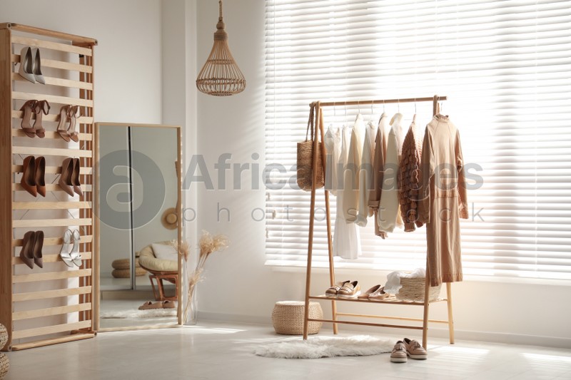 Modern dressing room interior with racks of stylish women's clothes and shoes