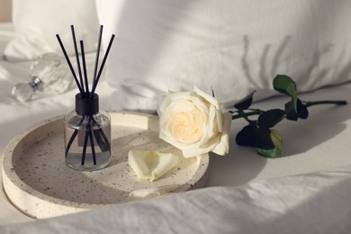 Aromatic reed air freshener and flower on bed