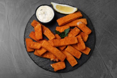 Tasty fresh fish fingers served on black table, top view