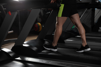 Man working out on treadmill in modern gym, closeup of legs