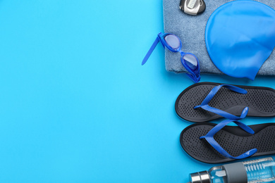 Flat lay composition with swimming accessories on blue background. Space for text