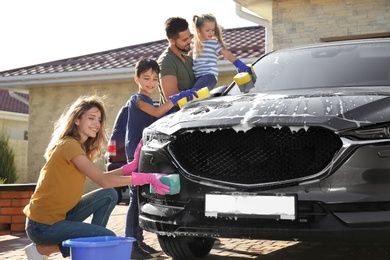 Happy family washing car at backyard on sunny day