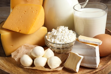 Photo of Different dairy products on wooden tray, closeup