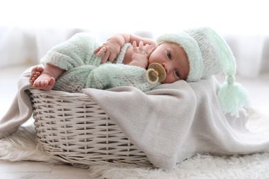 Cute newborn baby lying on plaid in basket at home