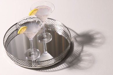 Photo of Elegant martini glasses with fresh cocktail and lemon slices on white table. Space for text
