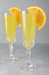 Glasses of Mimosa cocktail with garnish on marble table