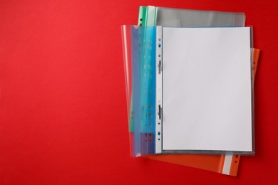 Photo of File folders with punched pockets on red background, flat lay. Space for text