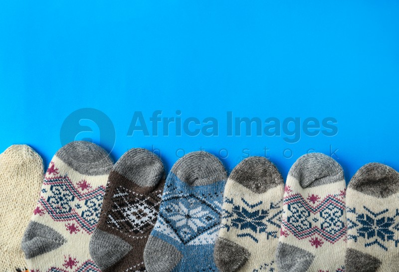 Soft knitted socks on blue background, flat lay with space for text. Winter clothes