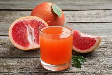 Tasty freshly made grapefruit juice and fruits on wooden table