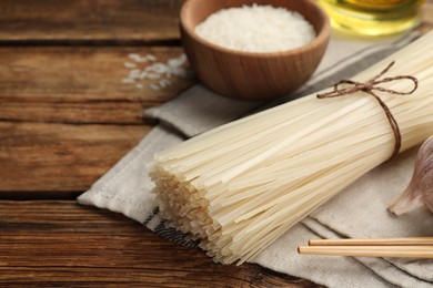 Photo of Uncooked rice noodles on wooden table, closeup. Space for text