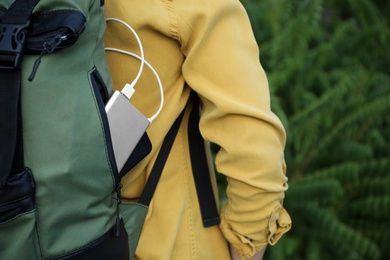 Photo of Woman with charging smartphone in backpack outdoors, closeup