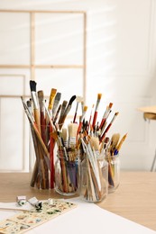 Different brushes, paints and palette on wooden table indoors. Artist's workplace