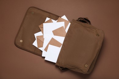 Postman bag with mails on brown background, top view