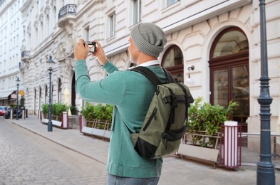 Traveler with backpack taking photo in foreign city during vacation