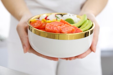 Photo of Woman holding delicious poke bowl with salmon, avocado and vegetables, closeup