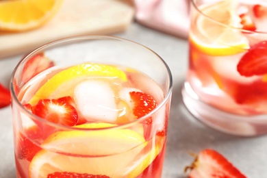 Photo of Tasty refreshing drink with strawberries and lemon on light grey table, closeup