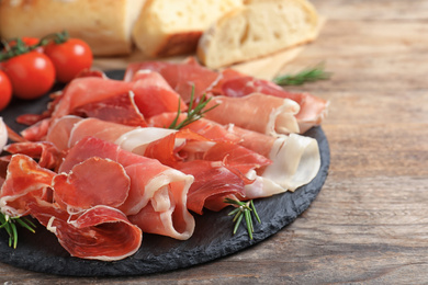 Pile of tasty prosciutto on wooden table, closeup