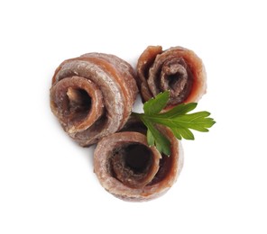Photo of Delicious rolled anchovy fillets and parsley on white background, top view