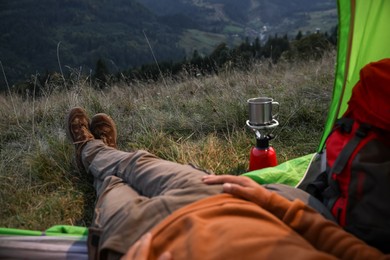 Man resting inside of camping tent in mountains, closeup