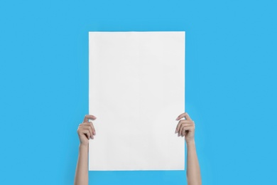 Woman holding blank poster on blue background, closeup