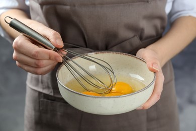 Woman whisking eggs in bowl, closeup view