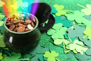 Pot with gold coins, hat and clover leaves on table, space for text. St. Patrick's Day celebration