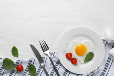 Romantic breakfast with heart shaped fried egg served on white wooden table, flat lay. Space for text