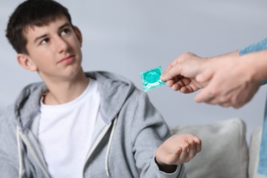Photo of Father giving condom to his teenage son at home, closeup. Sex education concept