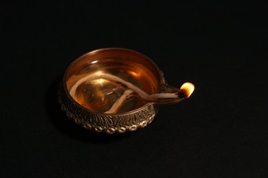 Photo of Lit diya on dark background, closeup. Diwali lamp