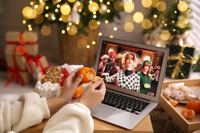 MYKOLAIV, UKRAINE - DECEMBER 25, 2020: Woman with tangerine watching The Witches  movie on laptop at home, closeup. Cozy winter holidays atmosphere